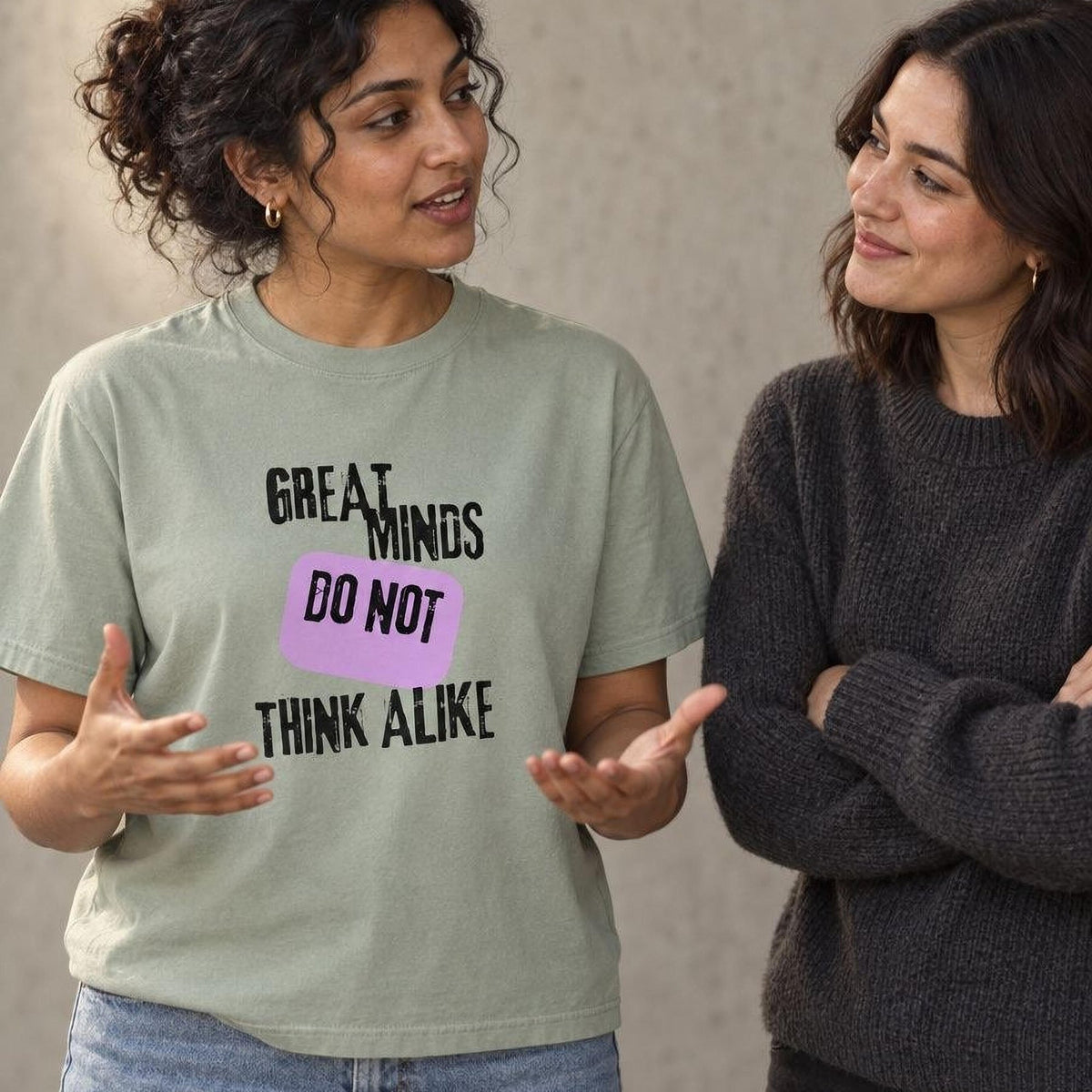 Two friends mid-conversation, one in a sage tee printed Great Minds Do Not Think Alike