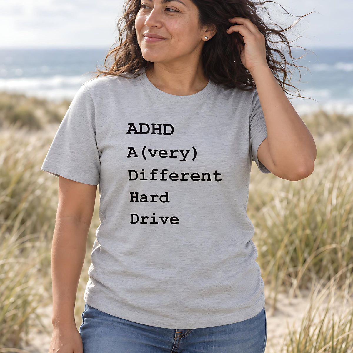 Woman on a windy beach in a grey tee printed ADHD: A (very) Different Hard Drive