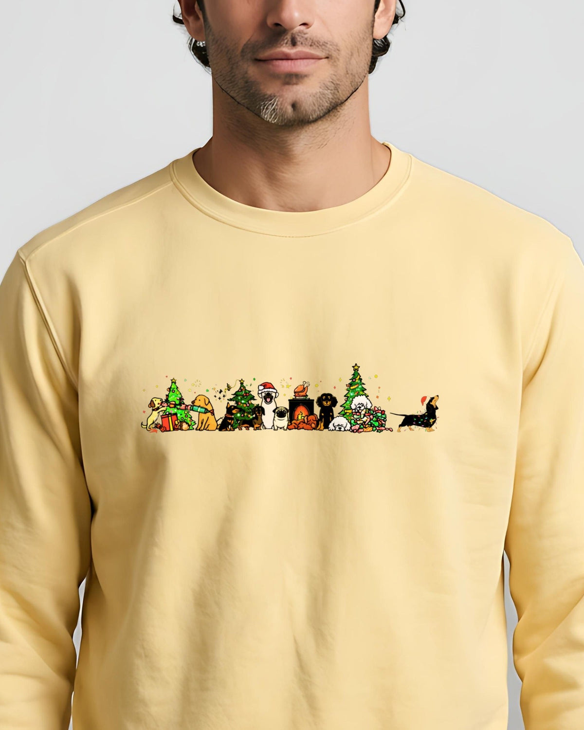 Man in a butter-yellow sweatshirt printed with a row of dogs celebrating Christmas around trees and a fireplace