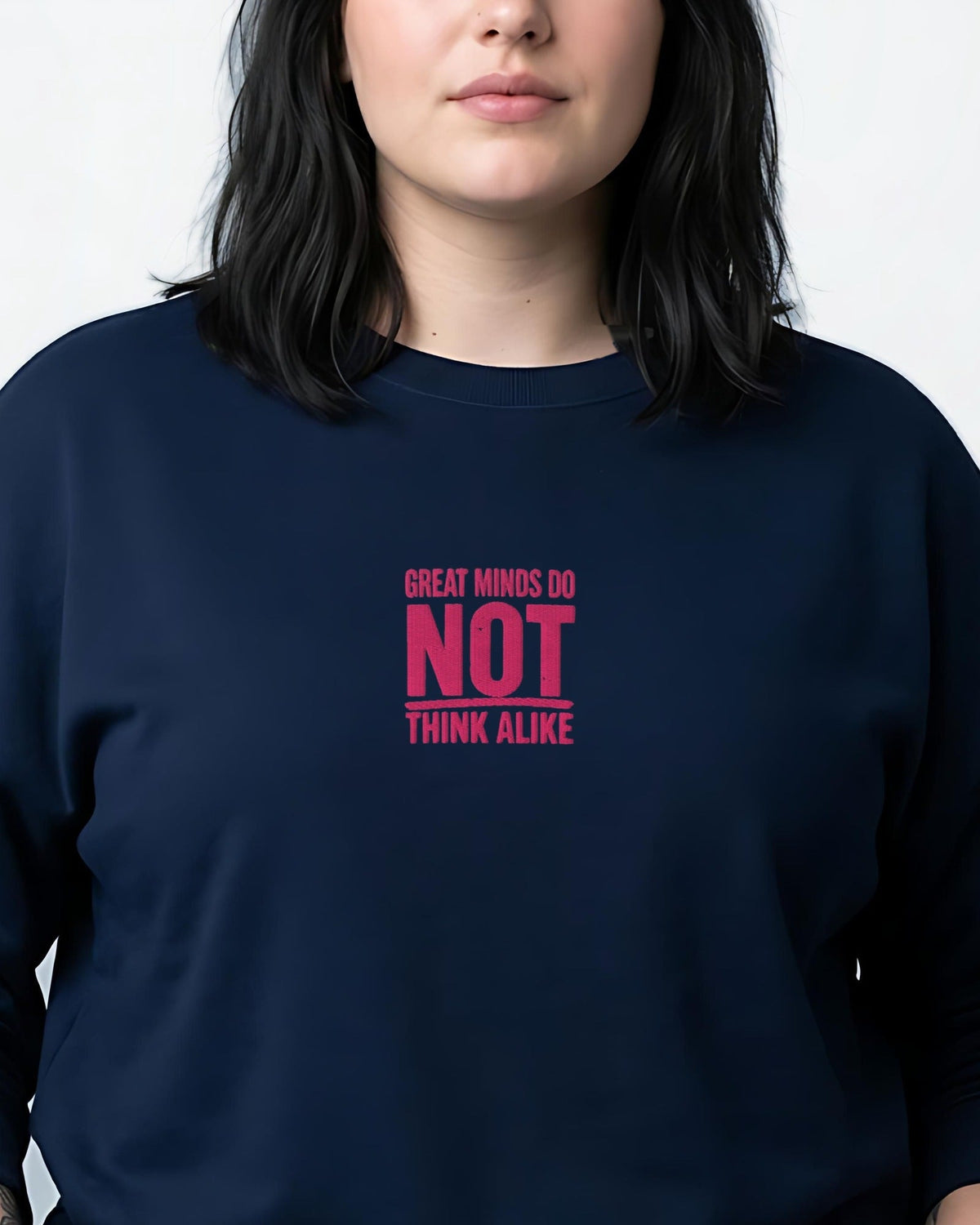 Woman in a navy sweatshirt embroidered Great Minds Do Not Think Alike in pink thread