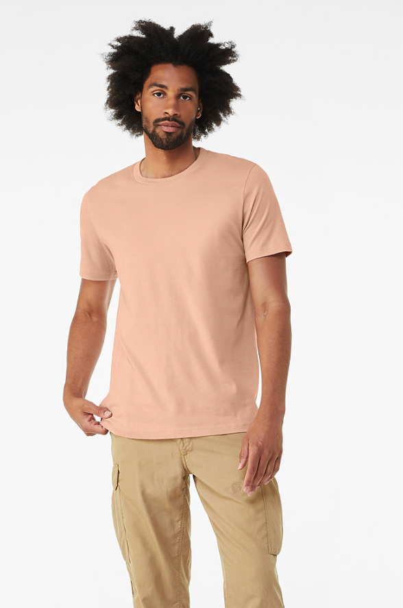 A man modeling a light peach crew-neck t-shirt and beige cargo pants with white sneakers, standing against a plain white studio background.