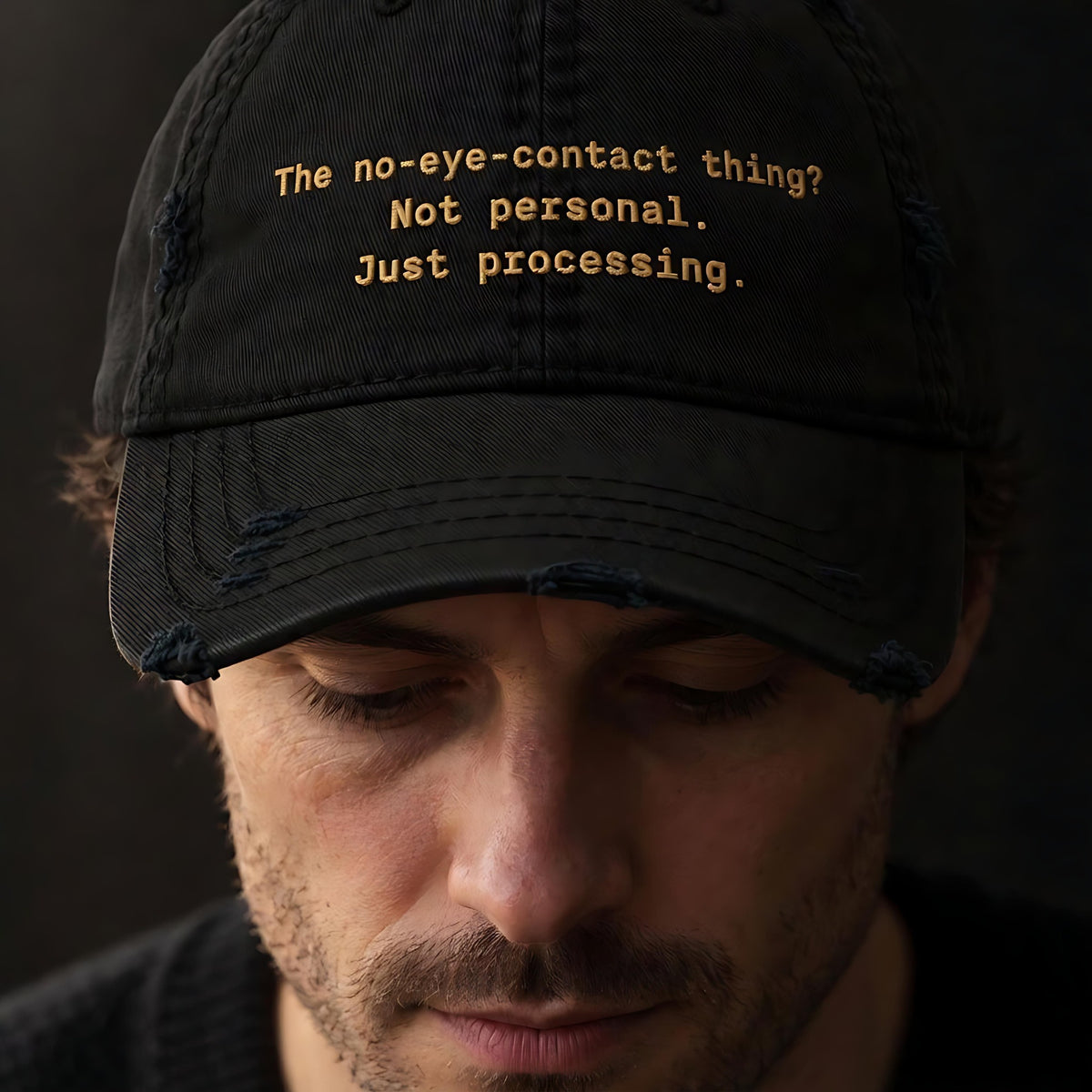 Man looking down in a black distressed dad hat embroidered The no-eye-contact thing? Not personal. Just processing.