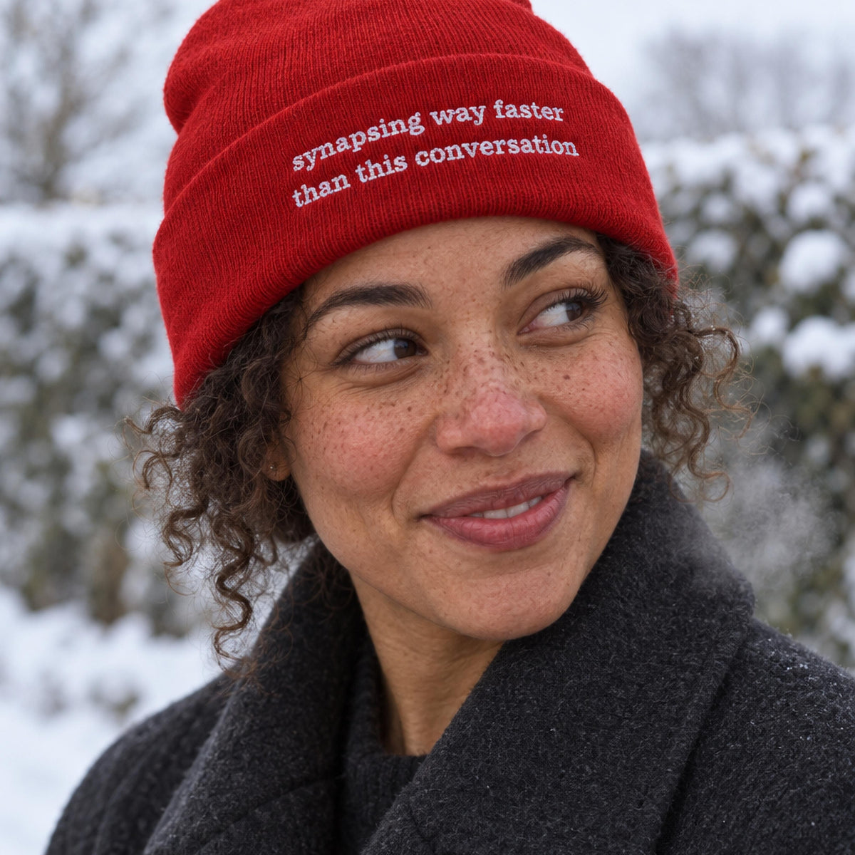 Woman in a red ribbed beanie embroidered with the words synapsing way faster than this conversation