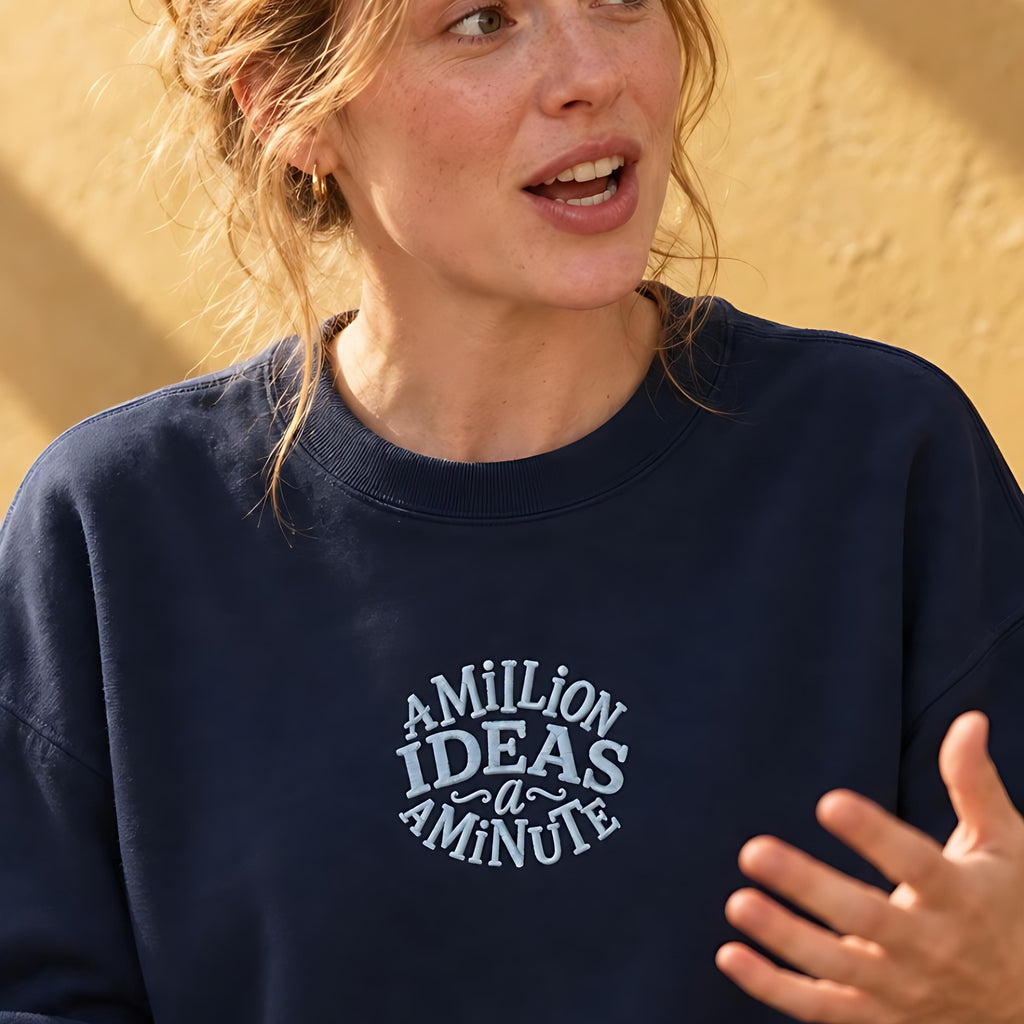 Woman in a navy organic sweatshirt embroidered with the words a million ideas a minute