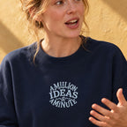 Woman in a navy organic sweatshirt embroidered with the words a million ideas a minute