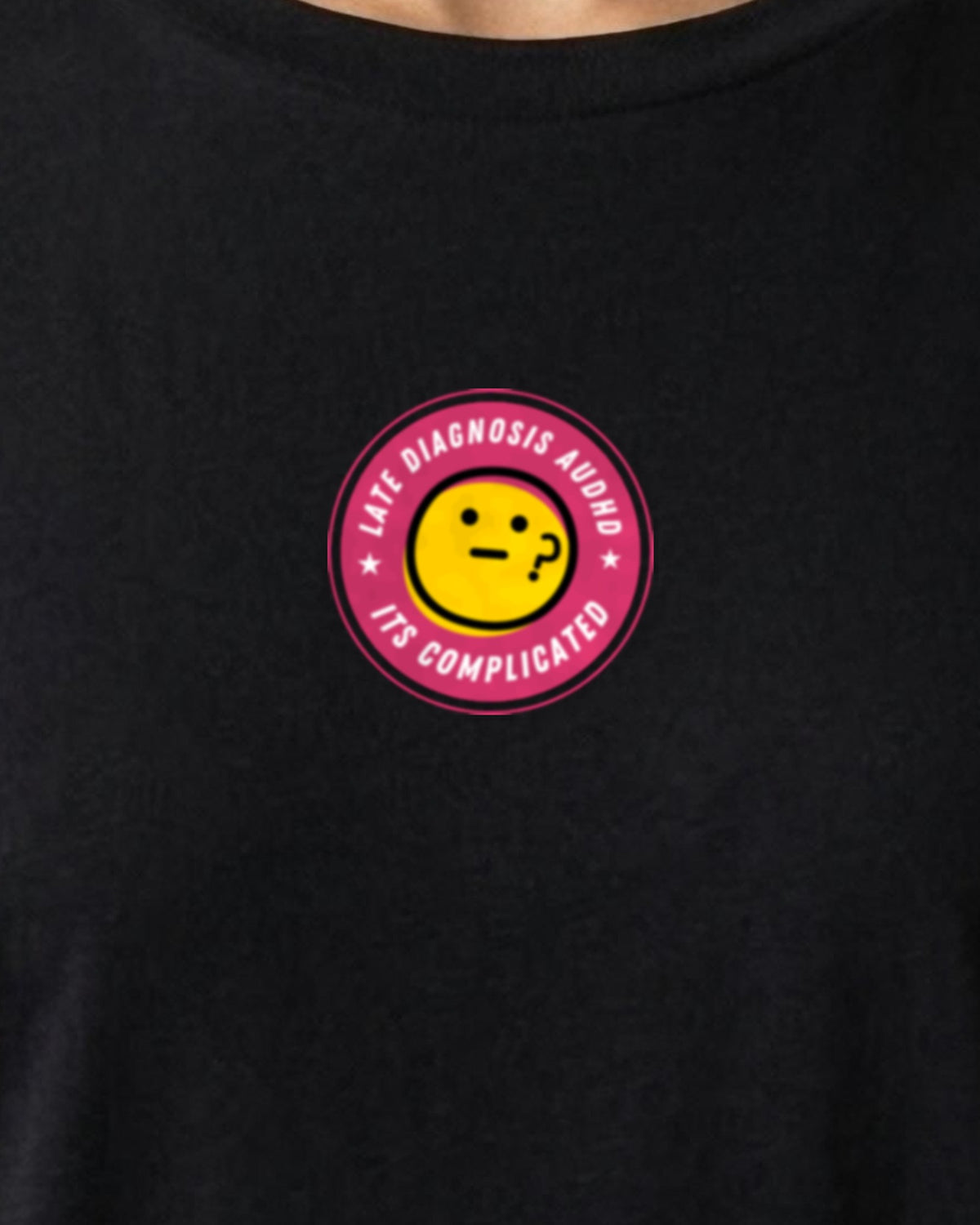 It's Complicated emoji (AuDHD) organic embroidered badge tee in Black, worn, close-up of the embroidered badge