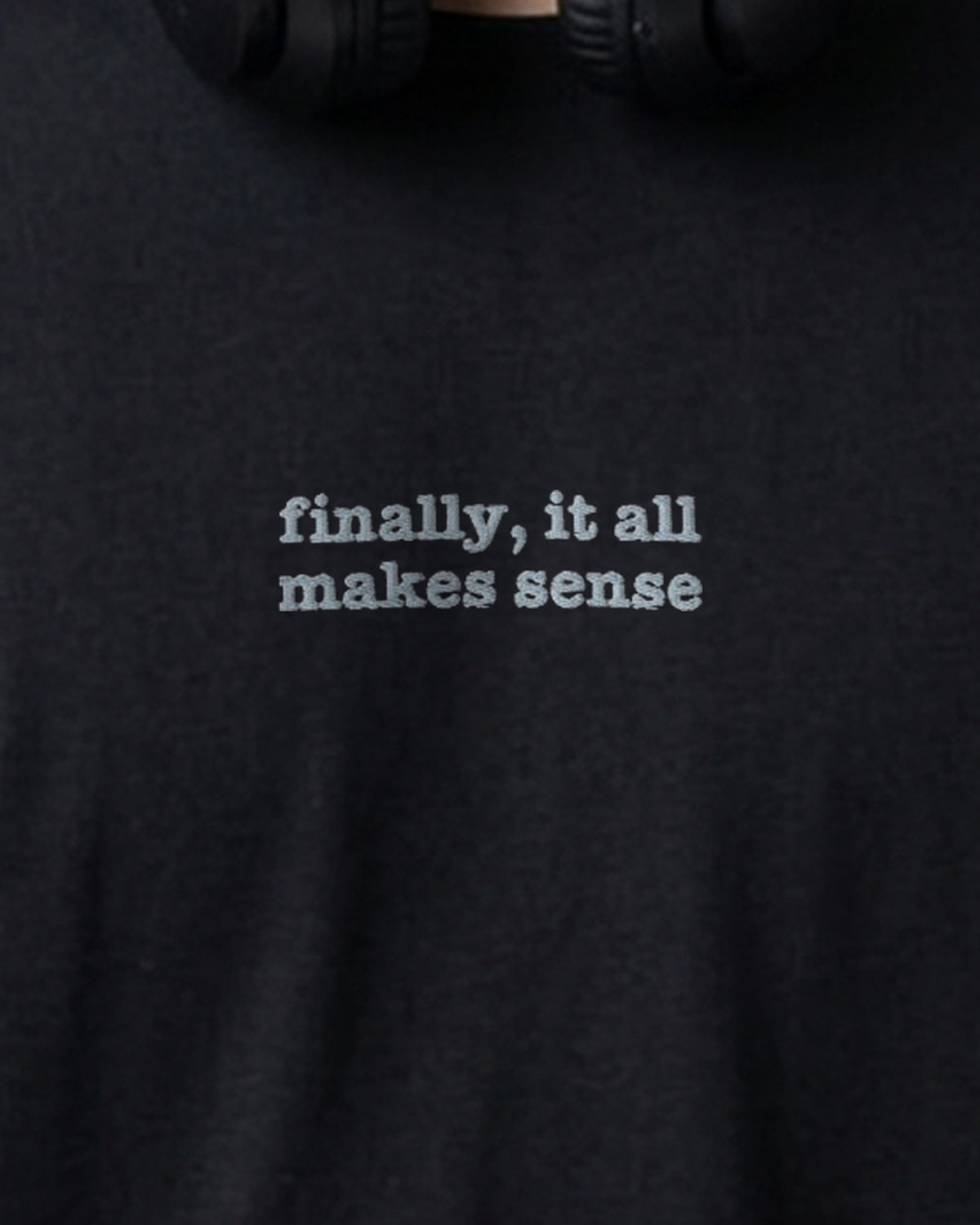 Finally embroidered organic tee in Black, worn, close-up of the chest embroidery