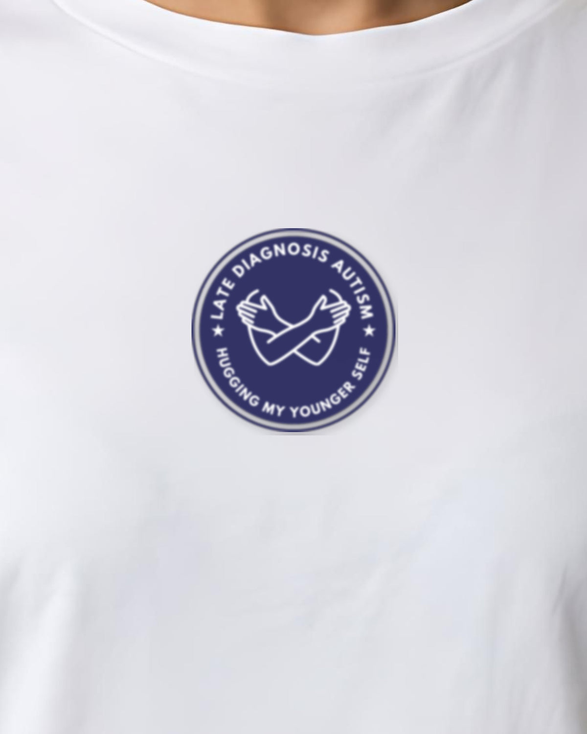 Hugging Autism organic embroidered badge tee in White, worn, close-up of the embroidered badge