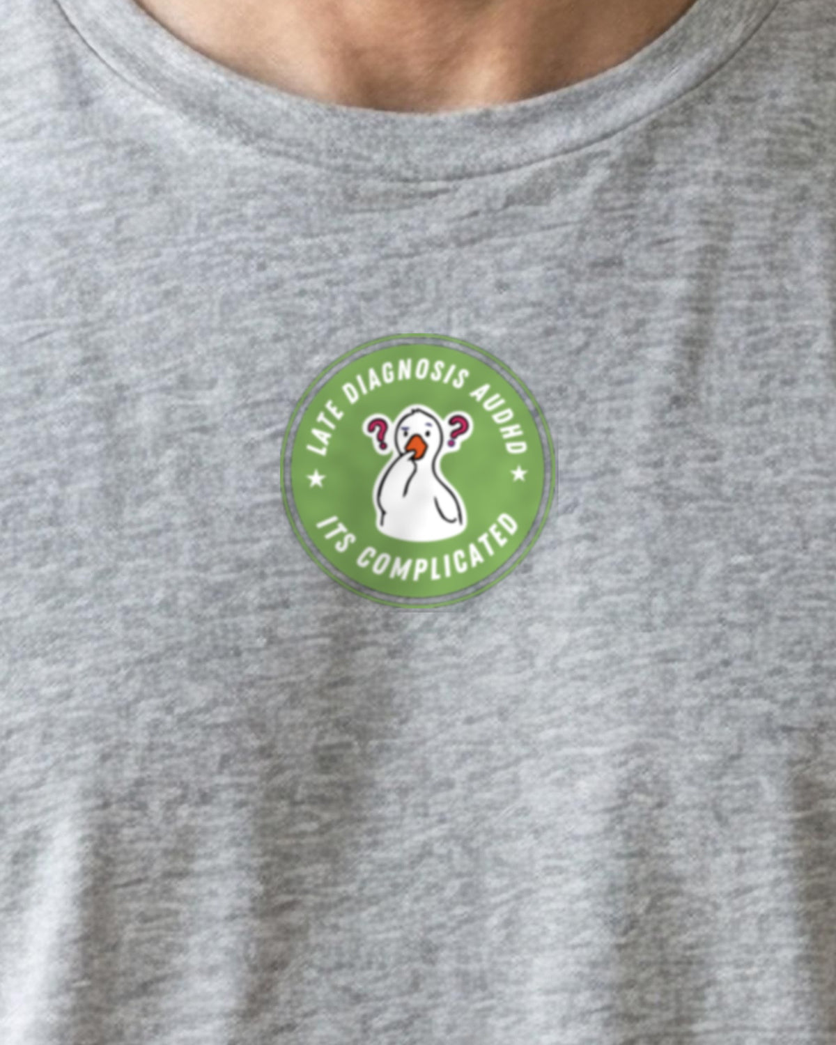 It's Complicated mouse (AuDHD) organic embroidered badge tee in Heather Grey, worn, close-up of the embroidered badge