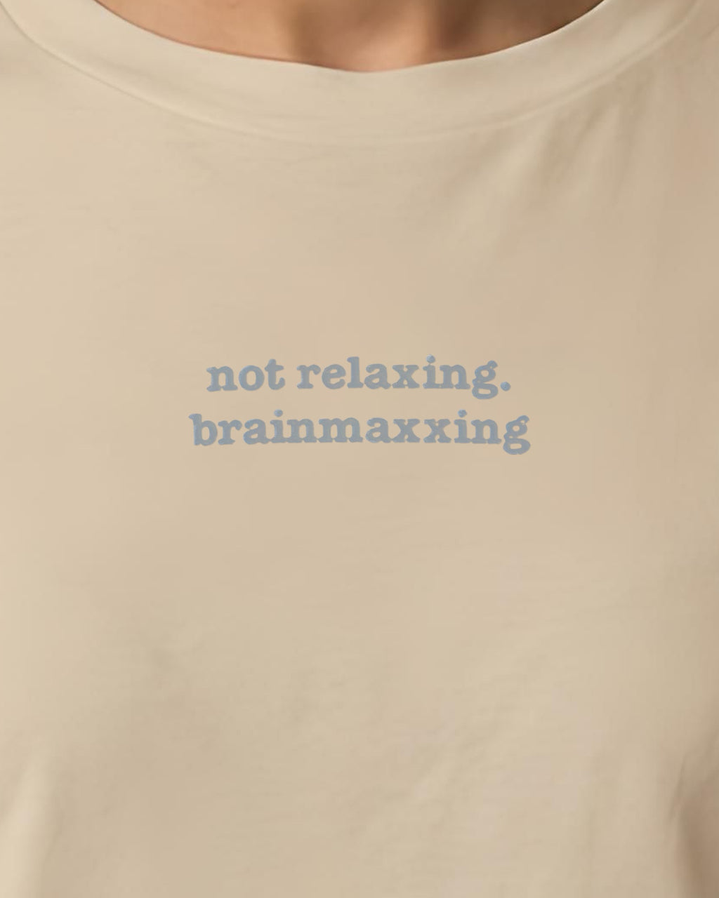 Not Relaxing. BrainMaxxing embroidered organic tee in Desert Dust, worn, close-up of the chest embroidery