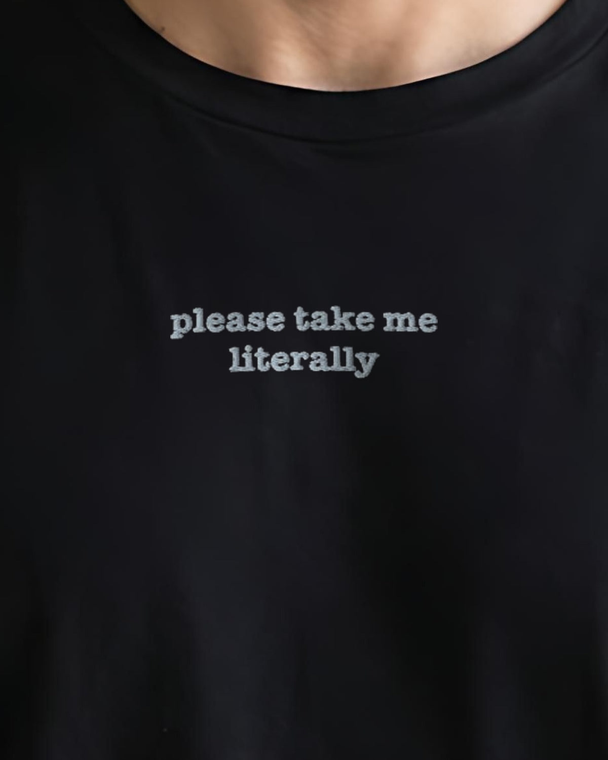 Please Take Me Literally embroidered organic tee in Black, worn, close-up of the chest embroidery