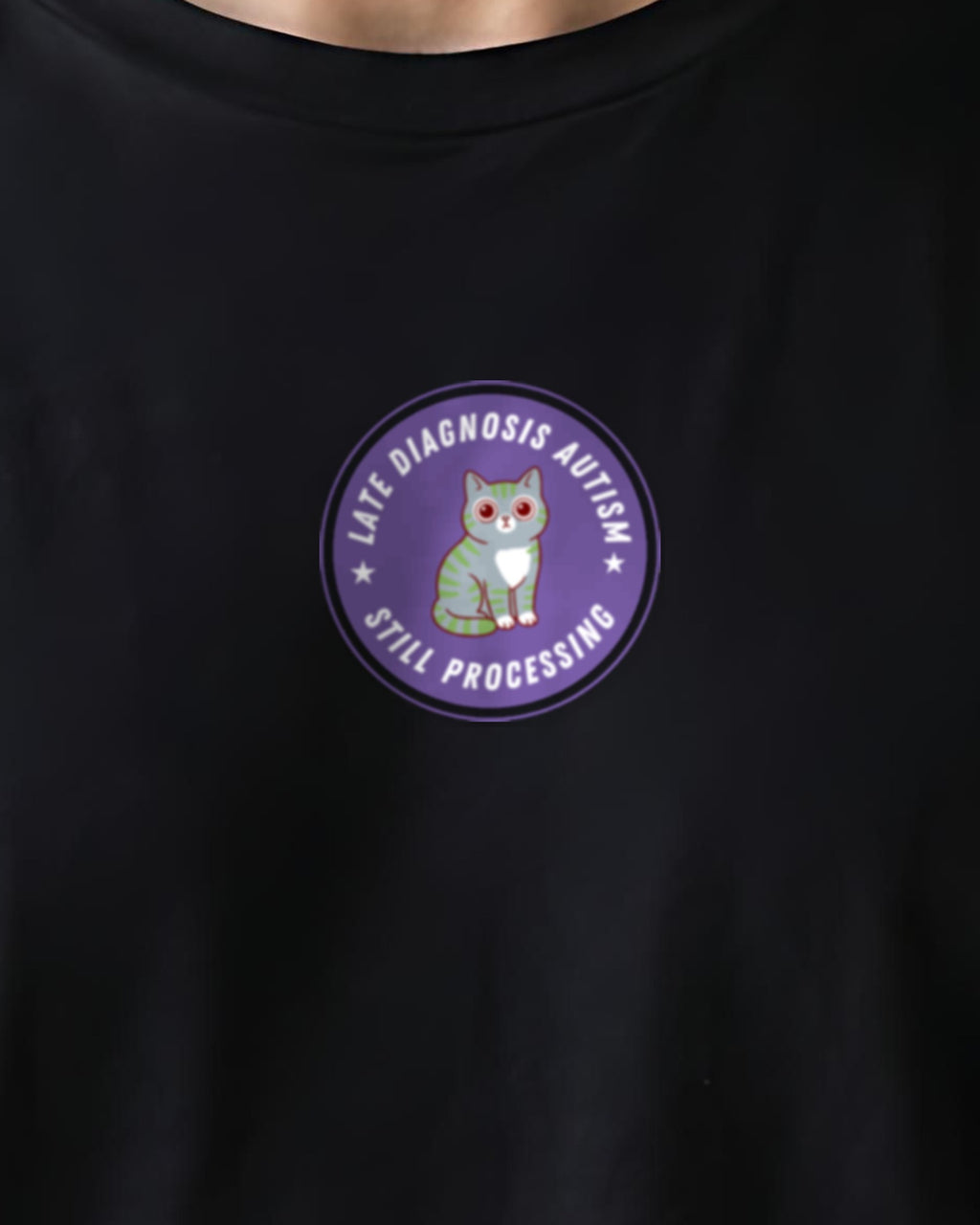 Still Processing organic embroidered badge tee in Black, worn, close-up of the embroidered badge