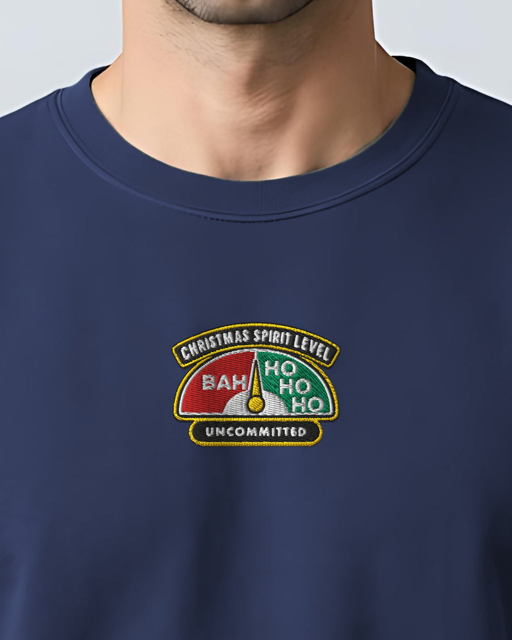 Christmas Spirit Level embroidered sweatshirt in True Navy, worn, close-up of the stitched gauge badge: Bah, Ho Ho Ho, Uncommitted